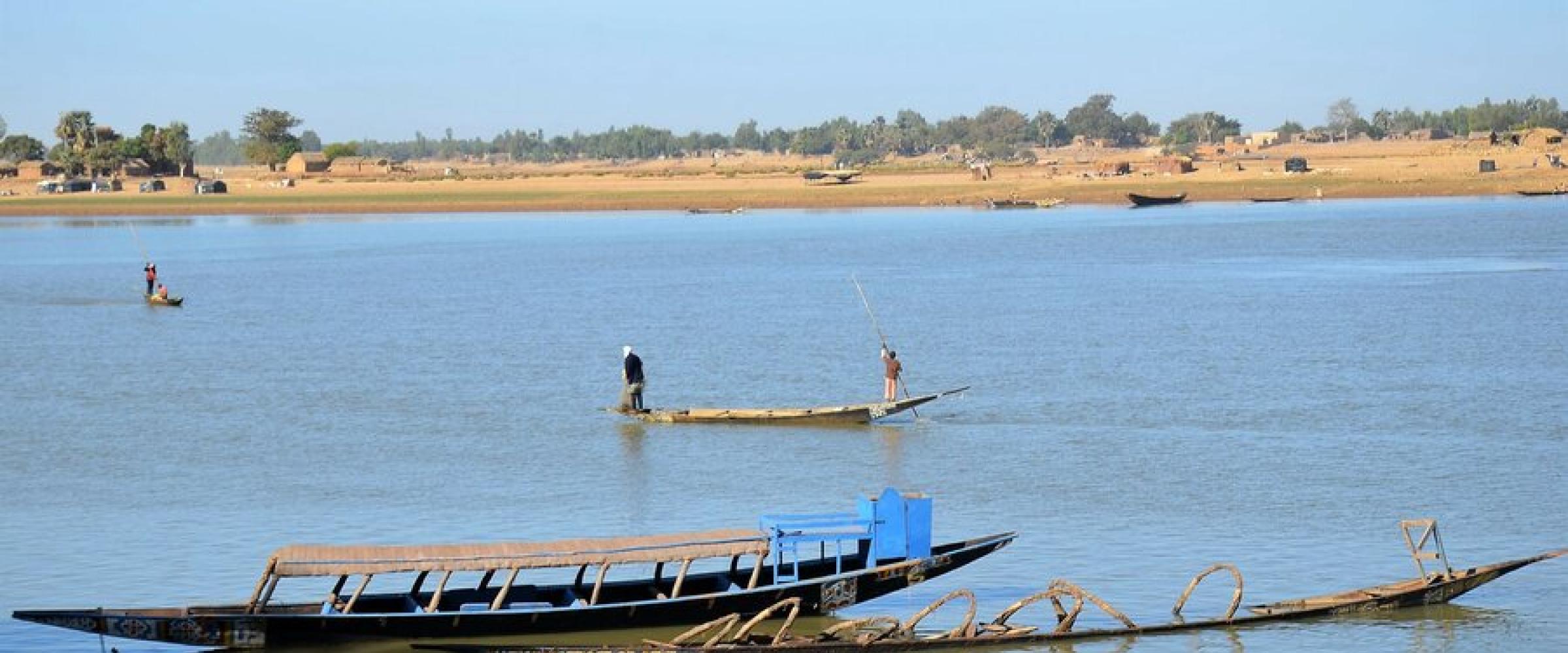 Pirogues sur un fleuve, village au bord de l'eau